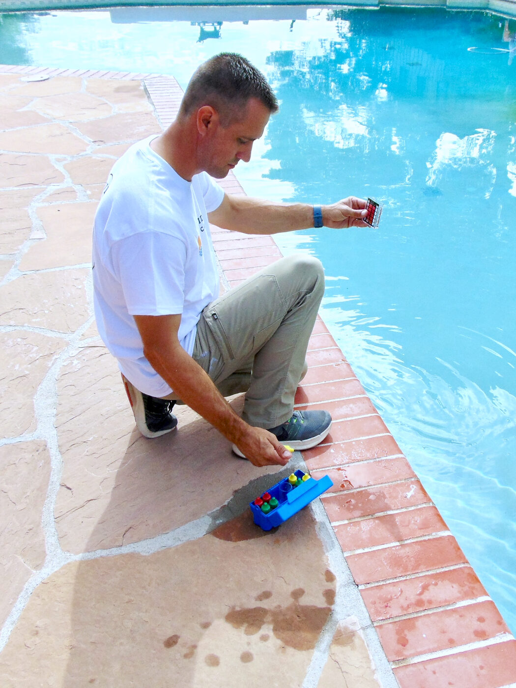 Josiah Linaman testing the water at the edge of a backyard pool